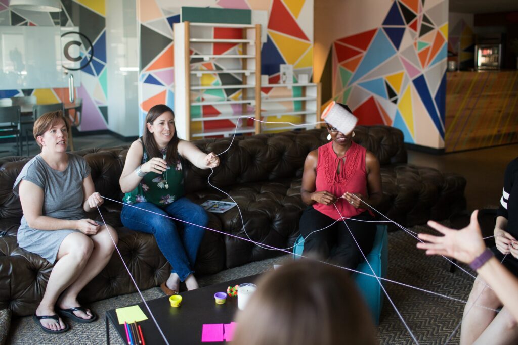 three women sitting on a couch playing with string