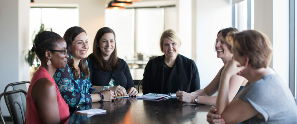 three women sitting at a table smiling for the camera